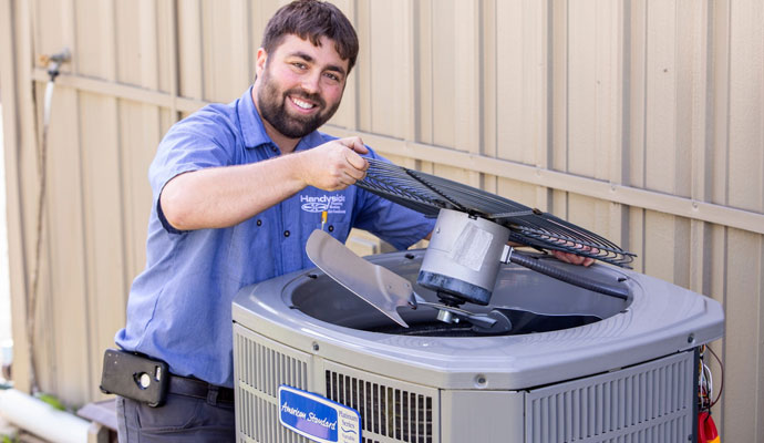 Technician repairing an outdoor air conditioning unit.