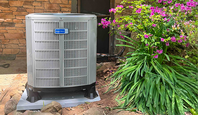 American Standard outdoor AC unit beside a house with plants