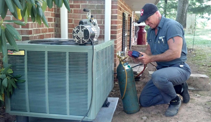 Technician performing maintenance on an outdoor HVAC unit