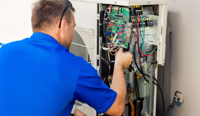 Technician repairing electrical components of an AC unit.