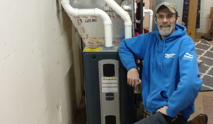 A technician posing next to a newly installed high-efficiency furnace system