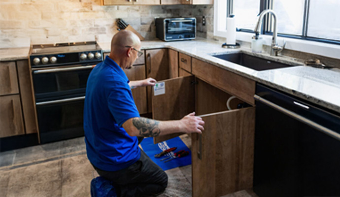 A professional of Handyside Plumbing, HVAC & Electrical inspecting kitchen sink pipe
